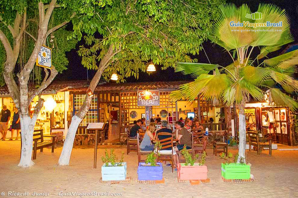 Imagem de turistas jantando em um restaurante na beira da praia.
